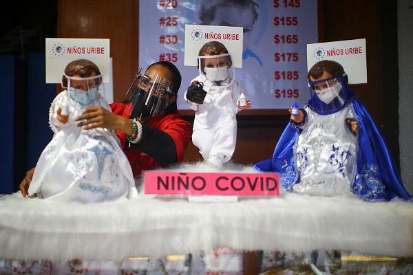 A saleswoman adjusts the suit of a dressed-up doll representing baby Jesus and wearing a face mask to promote the use of masks as a precautionary measure amid the Covid-19 outbreak before Christmas celebration, inside a store in Mexico City, Mexico. Credit: Reuters