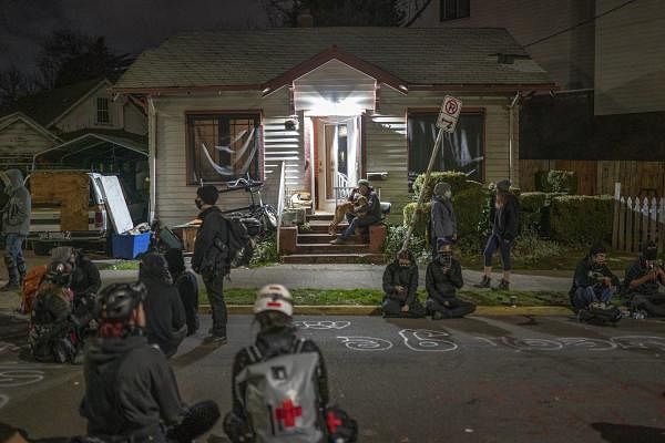 Protesters walk through an area near the Red House on Mississippi Street blockaded against a police response on December 9, 2020 in Portland, Oregon. Police and protesters clashed during an attempted eviction Tuesday morning, leading protesters to establish a barricade around the Red House. Credit: AFP