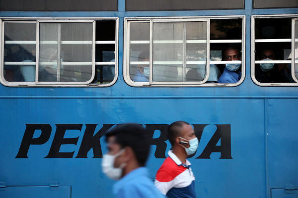 Workers look out from a bus after their shifts at a Top Glove factory in Klang, Malaysia. Credit: Reuters