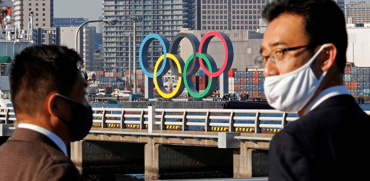 Men wearing face masks watch as giant Olympic rings, which were temporarily taken down in August for maintenance amid the coronavirus disease outbreak, are transported for reinstallation at the waterfront area at Odaiba Marine Park in Tokyo, Japan. Credit: Reuters