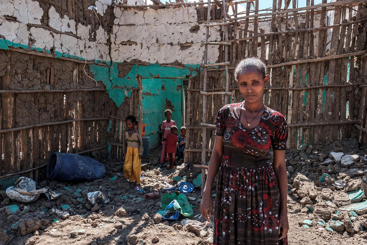 A woman stands with her children amidst the rubbles of her house that was damaged during the fightings that broke out in Ethiopia's Tigray region, in the village of Bisober. Credit: AFP