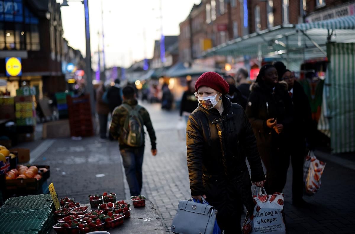 A shopper wearing a face covering due to the Covid-19 pandemic, looks at fruits and vegetables displayed for sale on a market stall at Walthamstow market, in Walthamstow, north east London ahead of fresh measures for the capital amid rising novel coronavirus infection rates. Credit: AFP