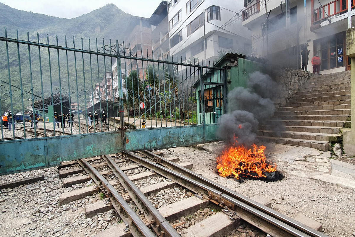 A pile of tyres burns at an entrance to the archaeological site of Machu Picchu during a protest by workers and residents of the area against the railway companies that offer service to the famous Inca citadel in demand of more train frequencies and cheaper rates, in the town of Machu Picchu, Peru. Credit: AFP
