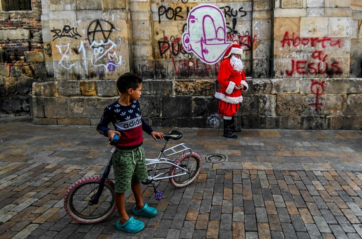 A Venezuelan migrant boy looks at a man dressed as Santa Claus in Bogota. Credit: AFP