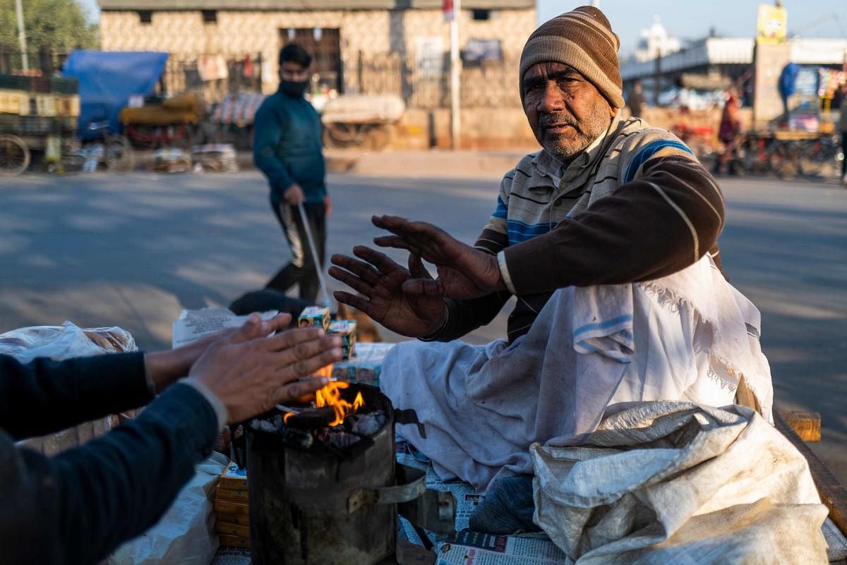 A vendor selling breakfast warms his hands from the fire of his stove on a cart during a cold winter morning in the old quarters of New Delhi. Credit: AFP