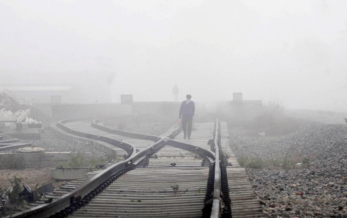 A man walks on a railway track amid dense fog on a cold winter morning, in Amritsar. Credit: PTI