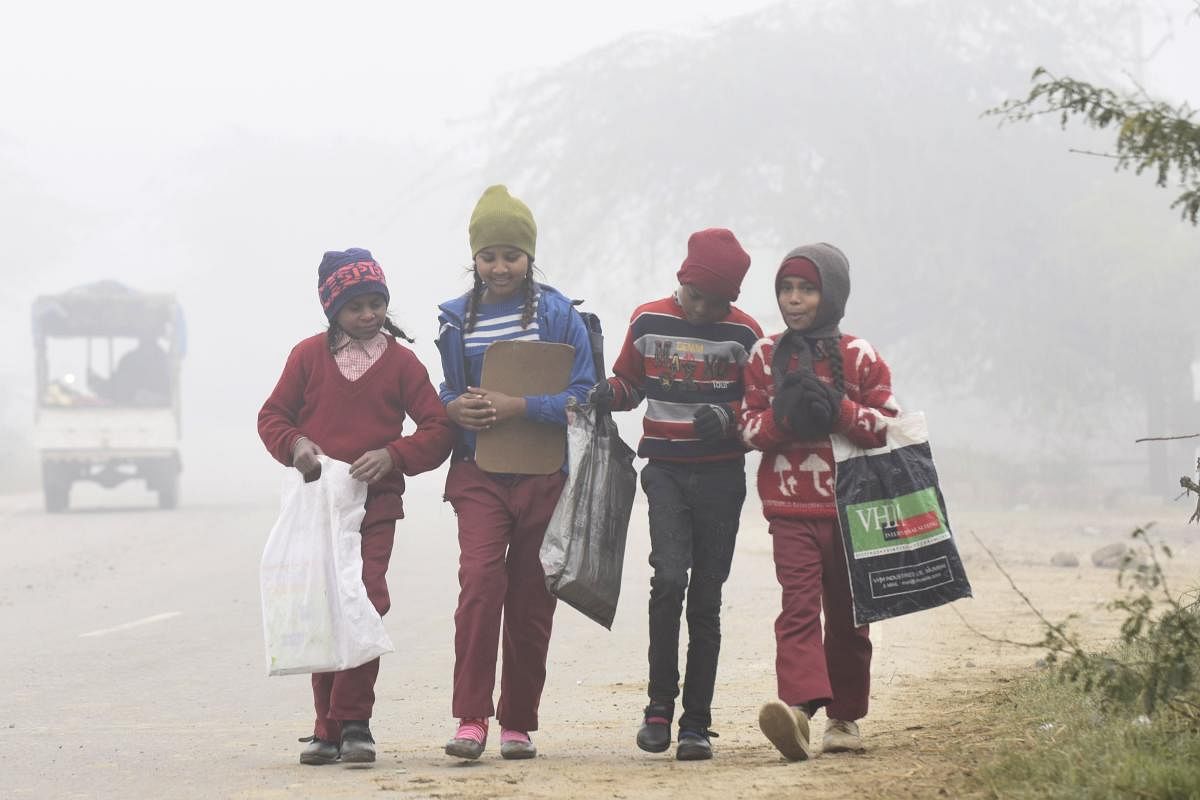Children walk to their school amid dense fog on a cold winter morning near the India-Pakistan Wagah Border Post, some 35 km from Amritsar. Credit: AFP