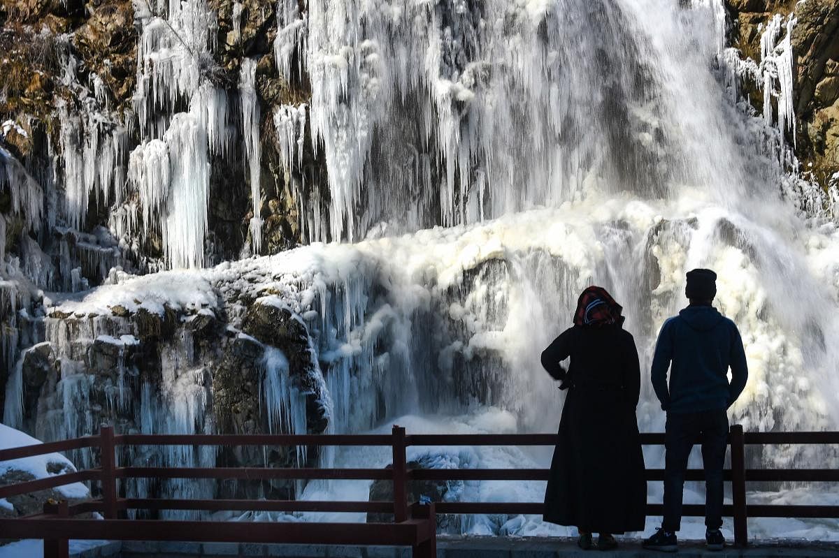A couple looks at a partially frozen waterfall, at Tangmarg in Baramulla District. Credit: PTI