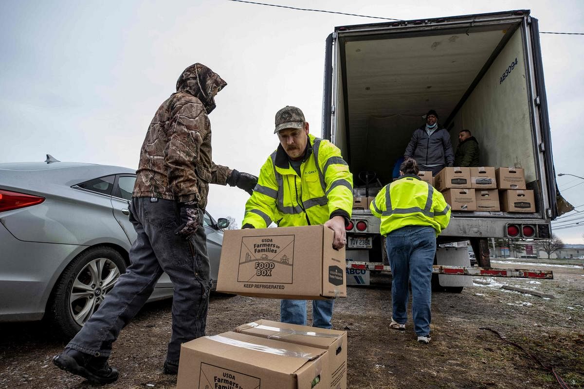 Volunteers work in an assembly line manner to unload a semi truck full of food boxes at the Athens County Fairgrounds in Athens, Ohio. Credit: AFP