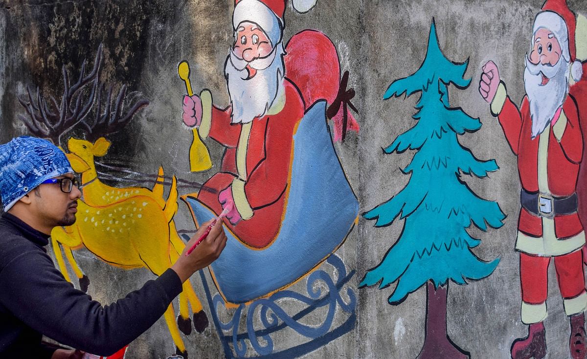 An artist draws a graffiti of Santa Claus on a wall, ahead of Christmas, in Nadia district, Monday, Dec. 21, 2020. Credit: PTI Photo