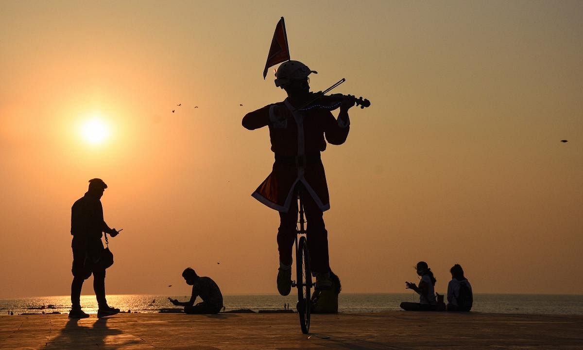 Imran Khan, resident of Mazgaon, wearing Santa Claus costume, plays the violin while riding a unicycle, ahead of the Christmas festival, at Bandra in Mumbai. Credit: PTI