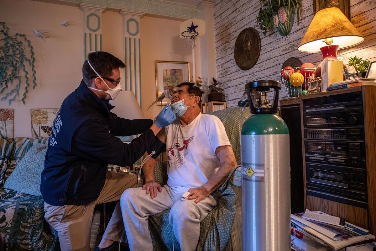 Community paramedic Lt. Richard Straub gives a rapid Covid-19 test to a patient, 79, during a home wellness check in White Plains, New York. Credit: AFP