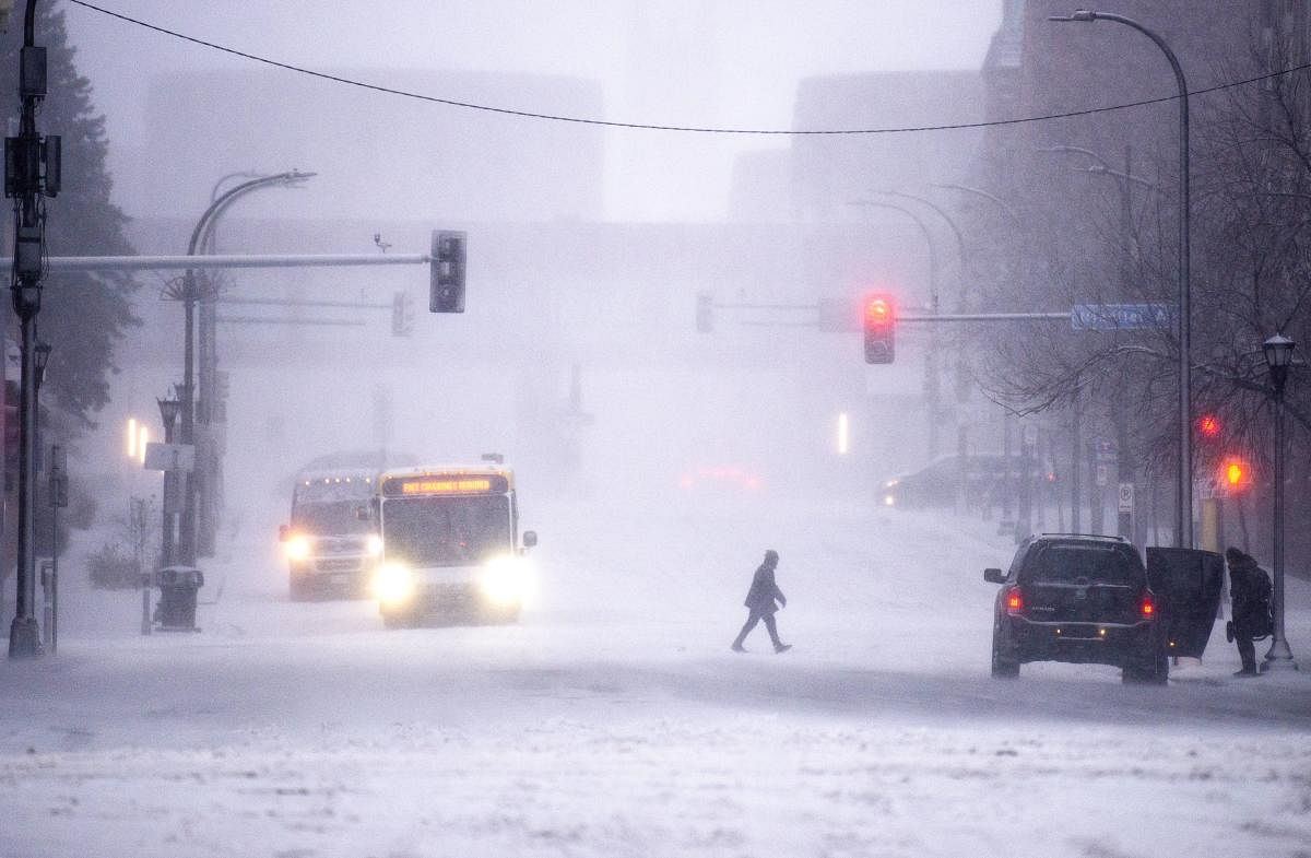 A person walks through downtown as snow falls in Minneapolis, Minnesota. Credit: AFP