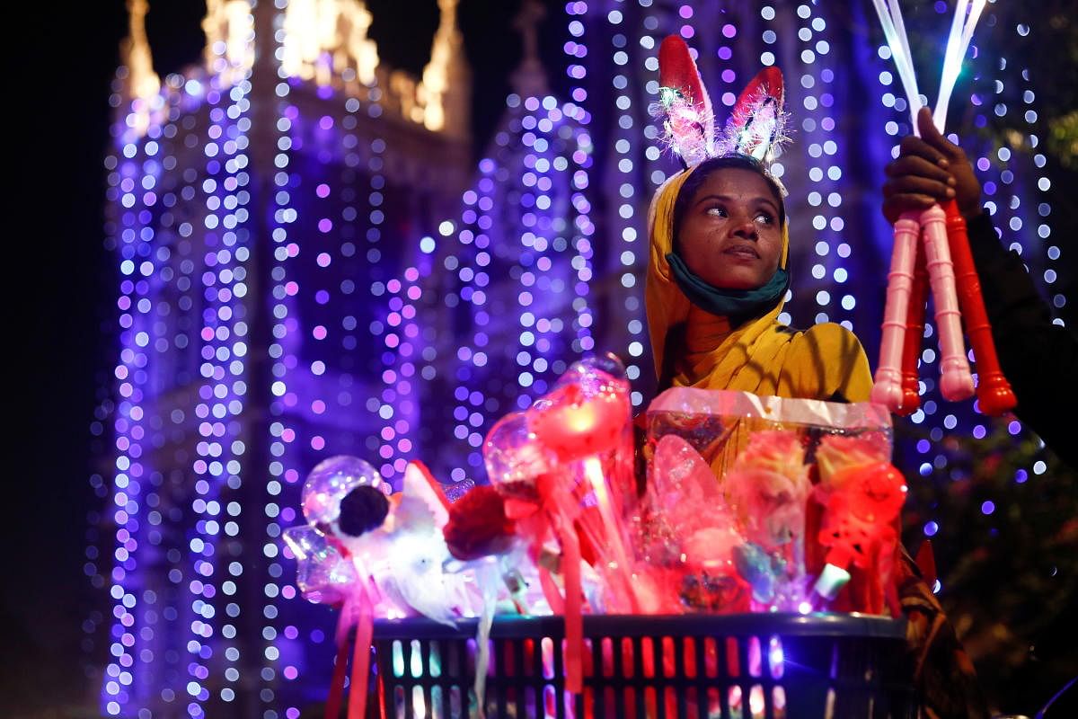 A woman sells props outside a church on as members of India's Christian community celebrate Christmas eve in Mumbai, India. Credit: AFP