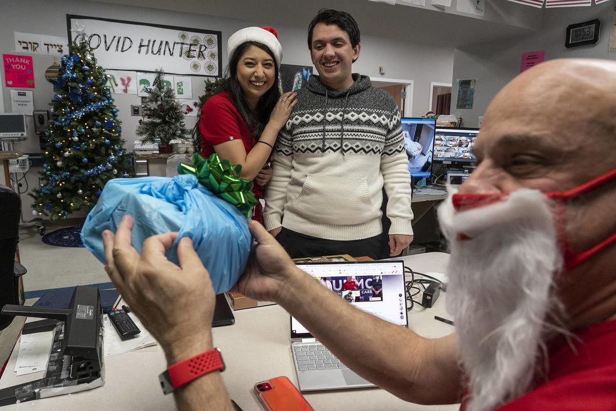 Dr. Joseph Varon reacts as he receives a Christmas present from medical staffs Elizabeth Gamboa, and Gabriel Cervera Rodriguez in nursing station of the Covid-19 intensive care unit (ICU) on Christmas Day at the United Memorial Medical Center in Houston, Texas. Credit: AFP