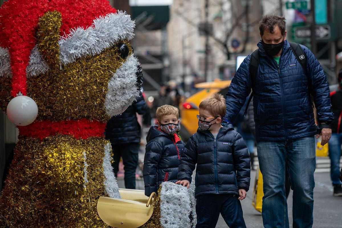 Children walk by a giant teddy bear with a Christmas hat in New York City. Credit: AFP