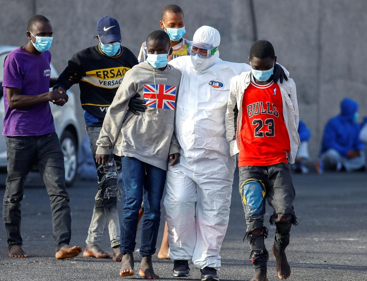 Migrants walk to be cared for by Red Cross members, in the port of Arguineguin, to the south part of the island of Gran Canaria, in Arguineguin, Spain. Credit: Reuters