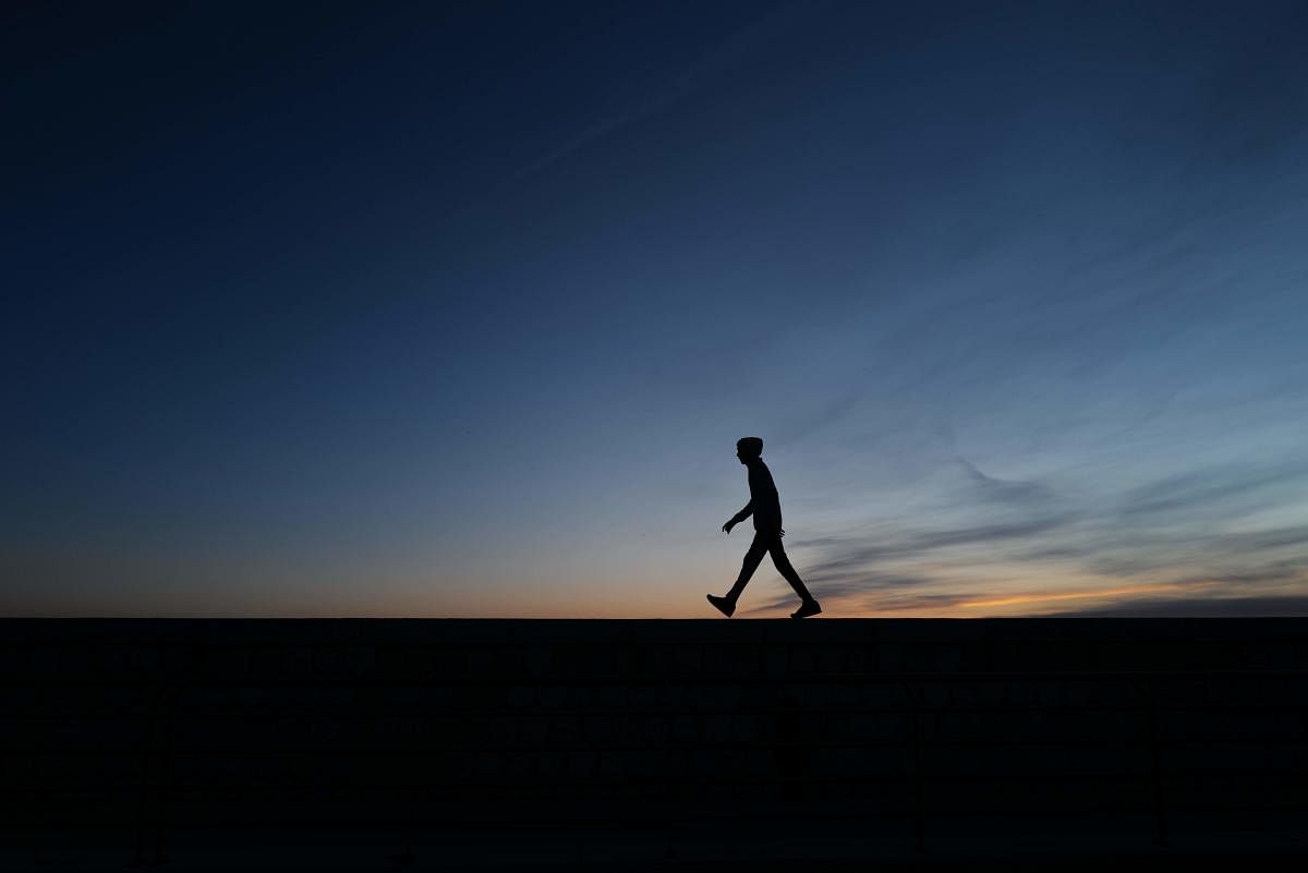A young man walks on the dock of the French riviera city of Nice, as the sun sets. Credit: AFP