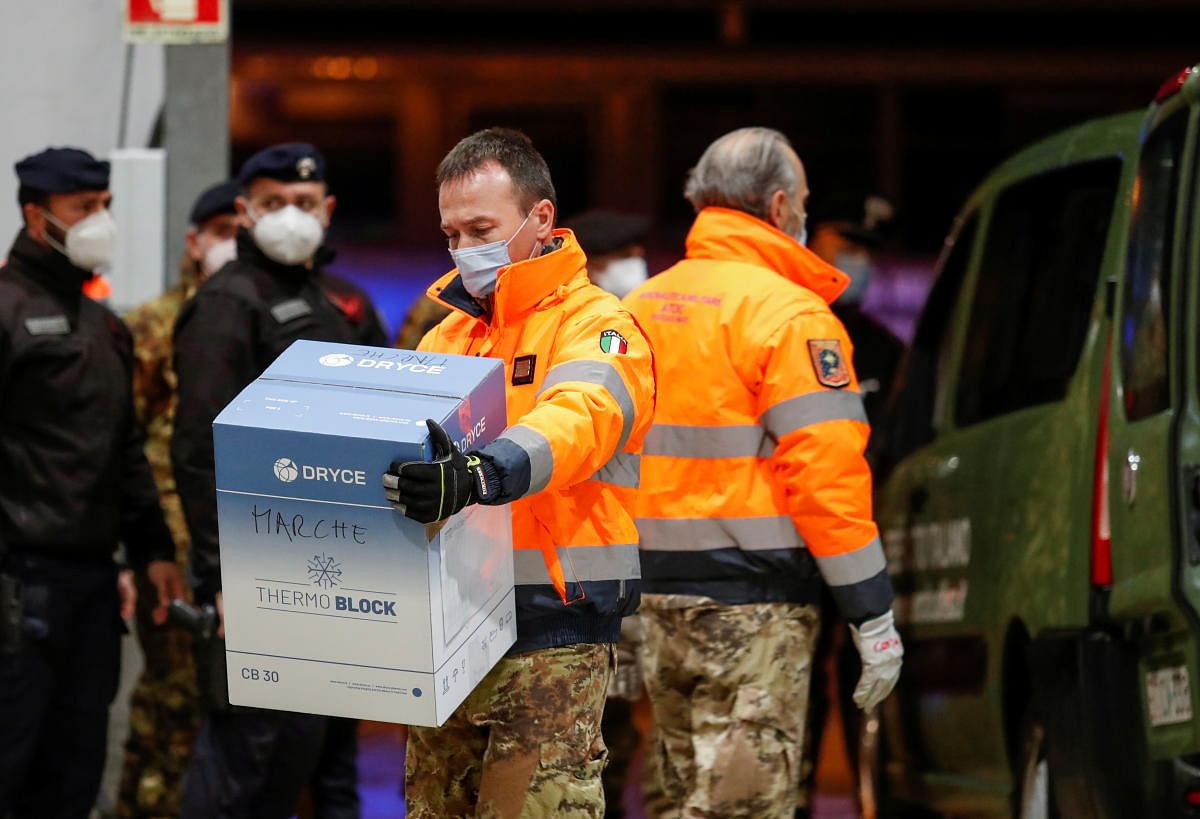 A member of the military carries a box containing the Pfizer-BioNTech Covid-19 vaccine to a hangar at Pratica di Mare Air Base near Rome, Italy. Credit: Reuters