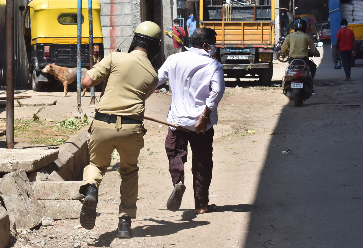 Crackdown on violators | Police cane a man defying the lockdown near Chamarajpet in Bengaluru. Credit: DH Photo/ Janardhan B K