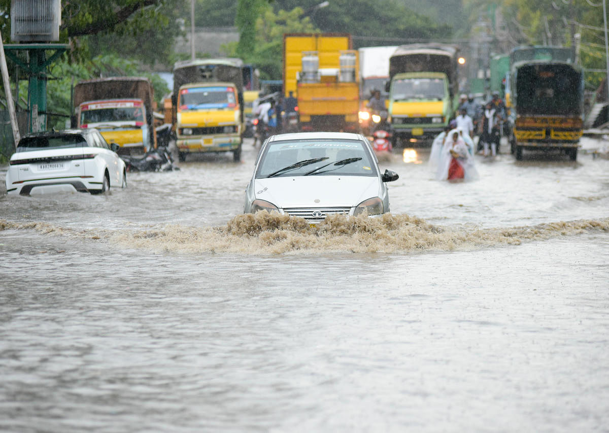 Ravaging virus, a deluge | Motorists and people struggle to get through a flooded road after heavy rains batter the Karnataka. Credit: DH Photo/ BH Shivakumar