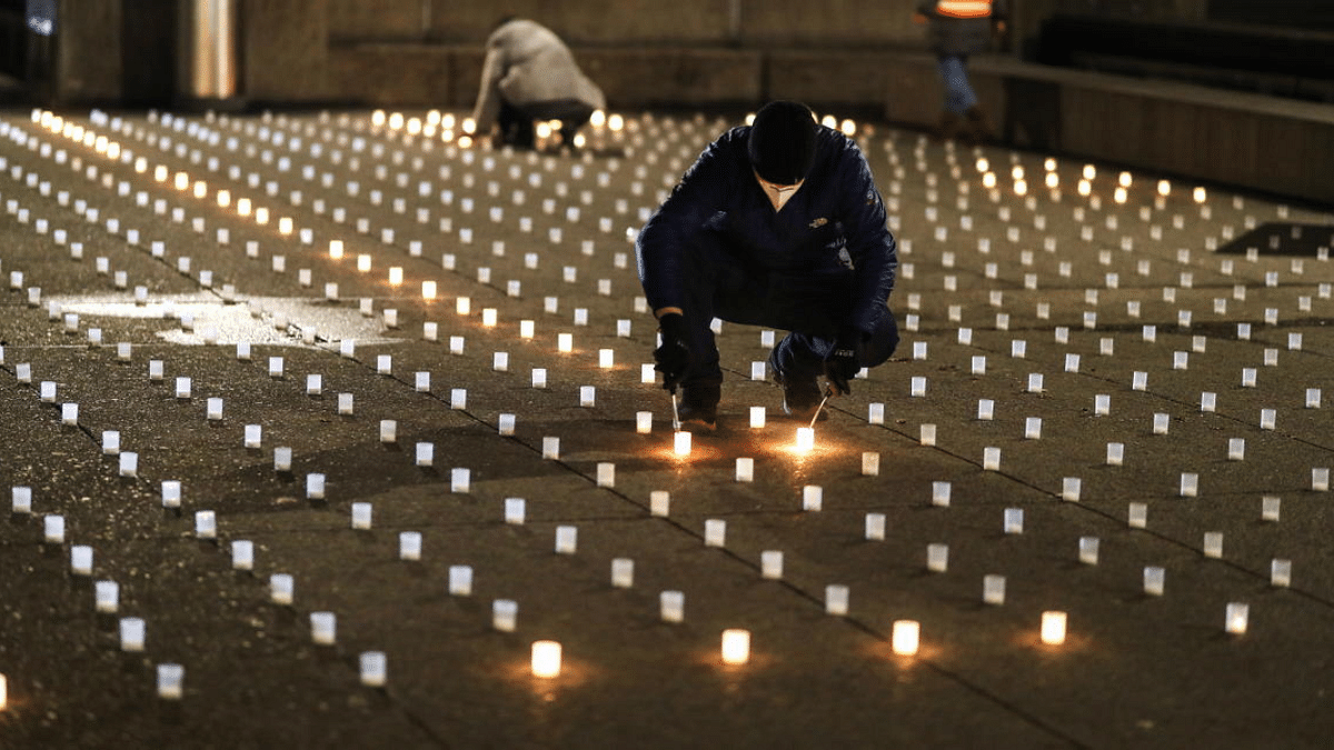 A man lights candles symbolizing the 886 Covid-19 victims in the Canton of Zurich during a candlelight vigil on the Gemuesebruecke bridge in front of the Grossmuenster church, as the spread of Covid-19 continues, in Zurich, Switzerland. Credit: Reuters