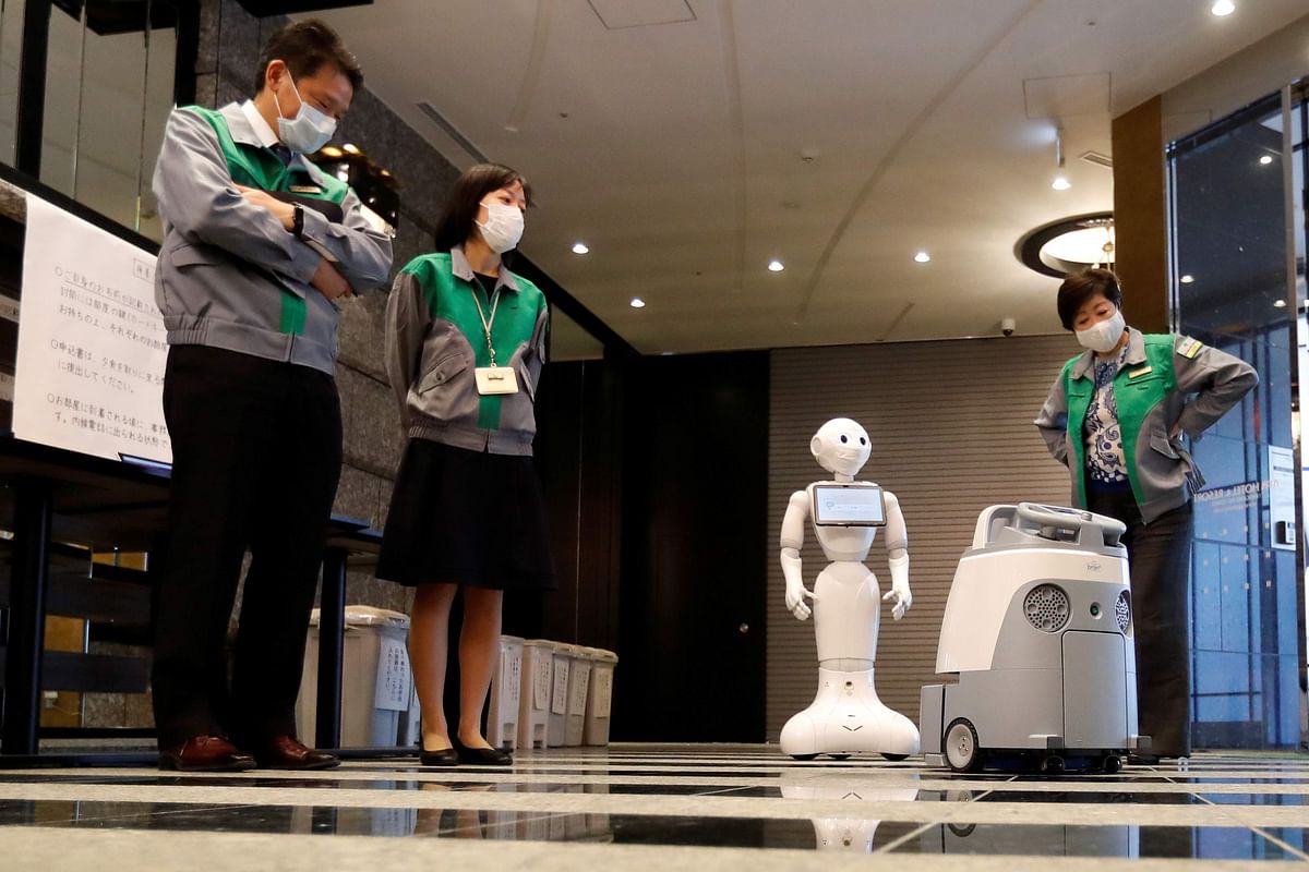 Tokyo Governor Yuriko Koike inspects a Pepper humanoid robot, manufactured by SoftBank Group Corp. and and cleaning robot Whiz a during a press preview of a hotel of APA Group that has been designated to accommodate asymptomatic people and those with light symptoms of the coronavirus disease. Credit: Reuters