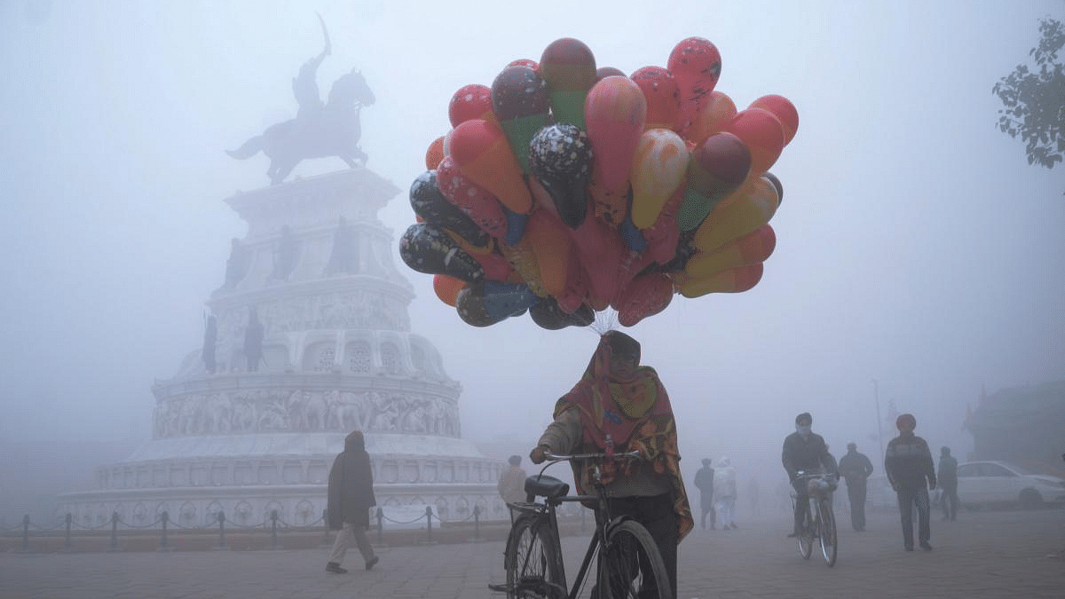 A balloon seller walks along Heritage street amid dense fog on a cold day on New Year's Day, in Amritsar. Credit: AFP