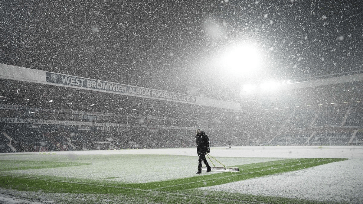 Groundstaff clear snow from the pitch ahead of the English Premier League football match between West Bromwich Albion and Arsenal at The Hawthorns stadium in West Bromwich, central England. Credit: AFP