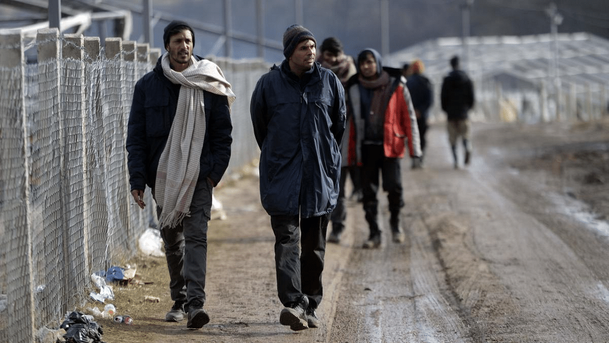 Migrants walk along a fence, at the Lipa camp near the north-western Bosnian town of Bihac. Credit: AFP Photo