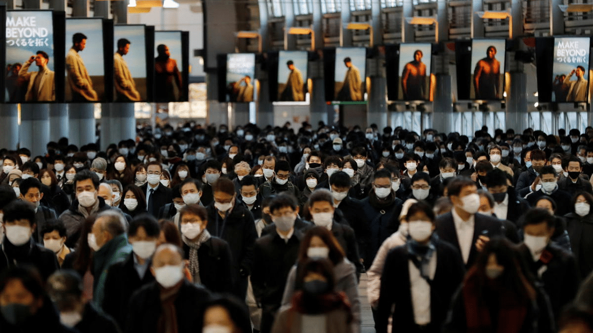 Commuters wearing protective masks, amid the Covid-19 outbreak, make their way at Shinagawa station in Tokyo, Japan. Credit: Reuters Photo