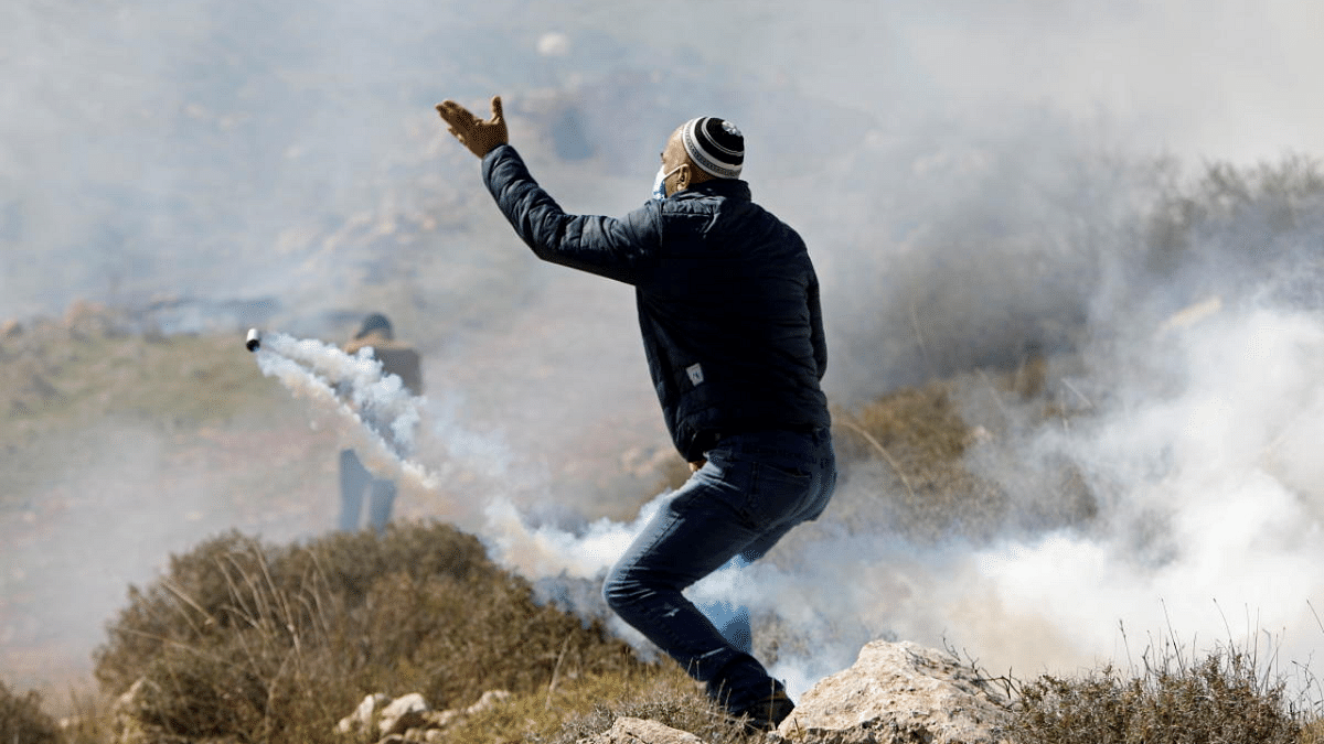 A Palestinian demonstrator reacts to tear gas fired by Israeli forces during a protest against Israeli settlements, in Beit Dajan in the Israeli-occupied West Bank. Credit: Reuters Photo