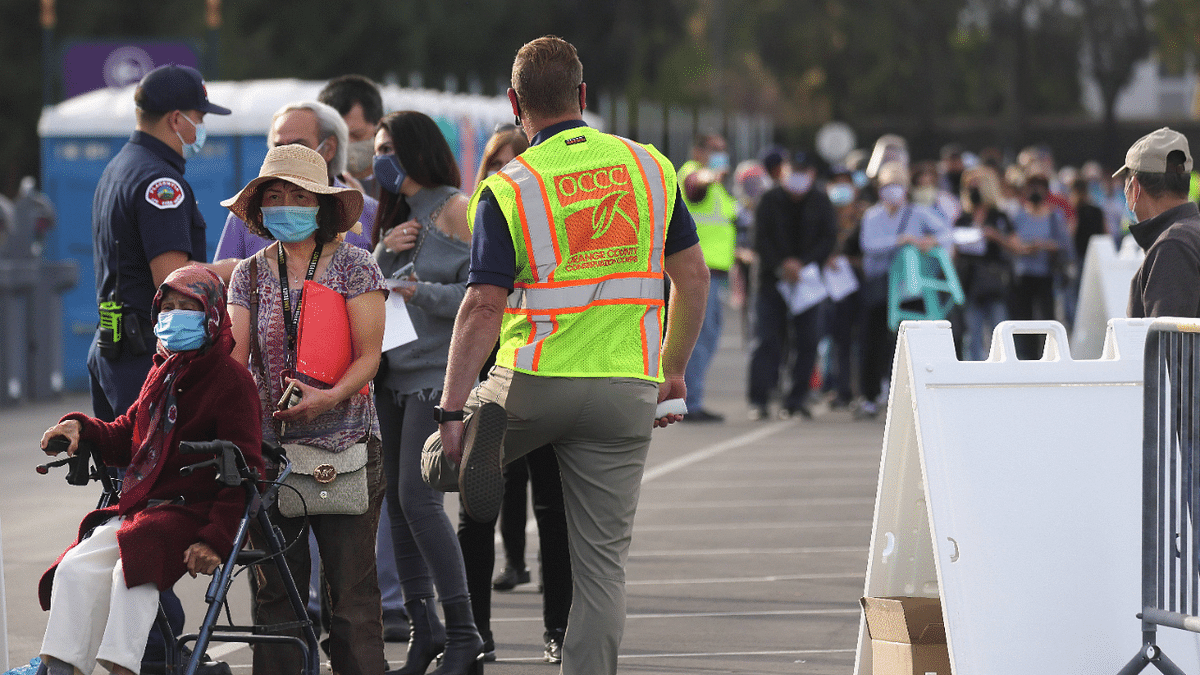 People wait in line to receive the Covid-19 vaccine at a mass vaccination site in a parking lot for Disneyland Resort in Anaheim, California. Credit: AFP Photo