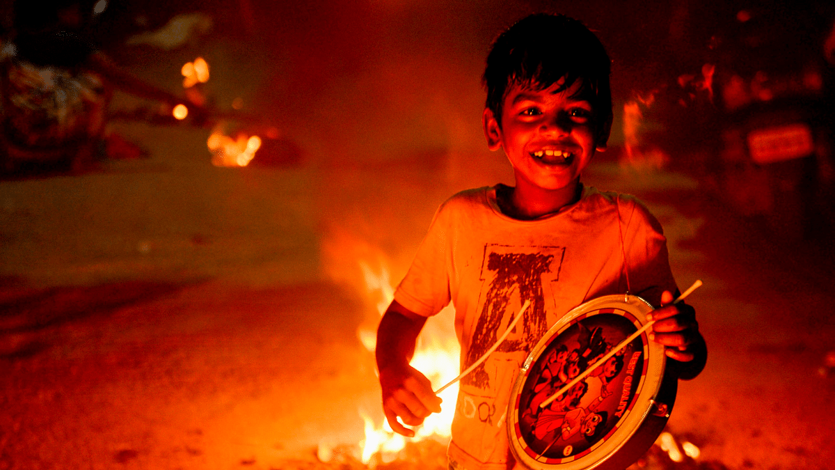 A boy plays the drum beside bonfires to celebrate Hindu harvest festival of Ponga in Chennai. Credit: AFP Photo