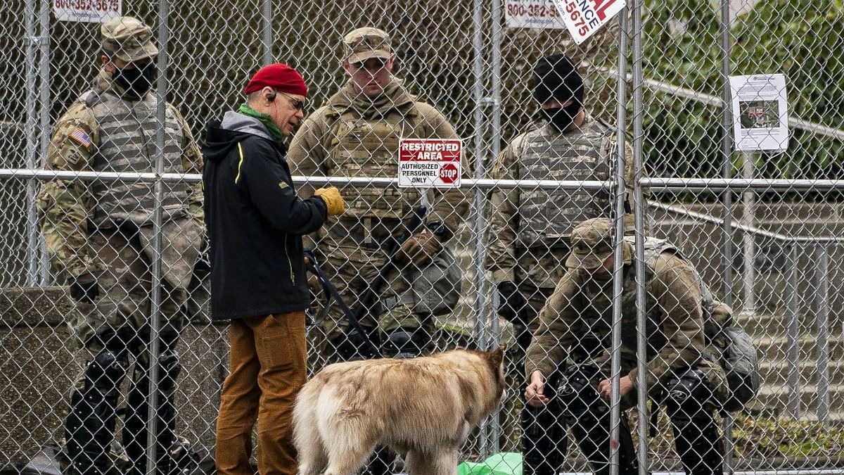 Washington National Guard personnel visit with a passerby and their dog while keeping watch at the Washington State Capitol on January 17, 2021 in Olympia, Washington. Credit: AFP Photo
