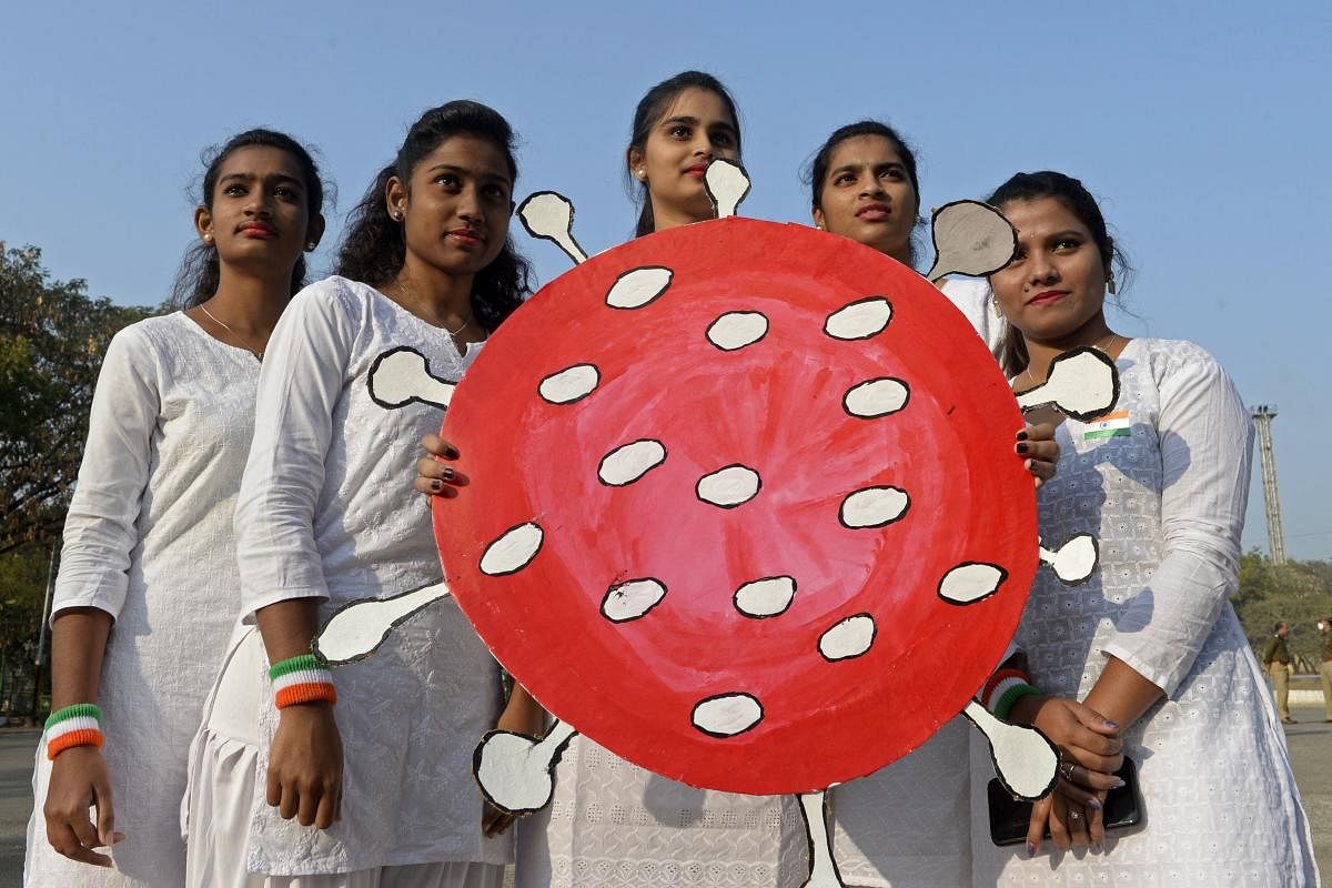 Youth hold a Covid-19 coronavirus-themed board during the Republic Day celebrations in Secunderabad, the twin city of Hyderabad on January 26, 2021. Credit: AFP Photo