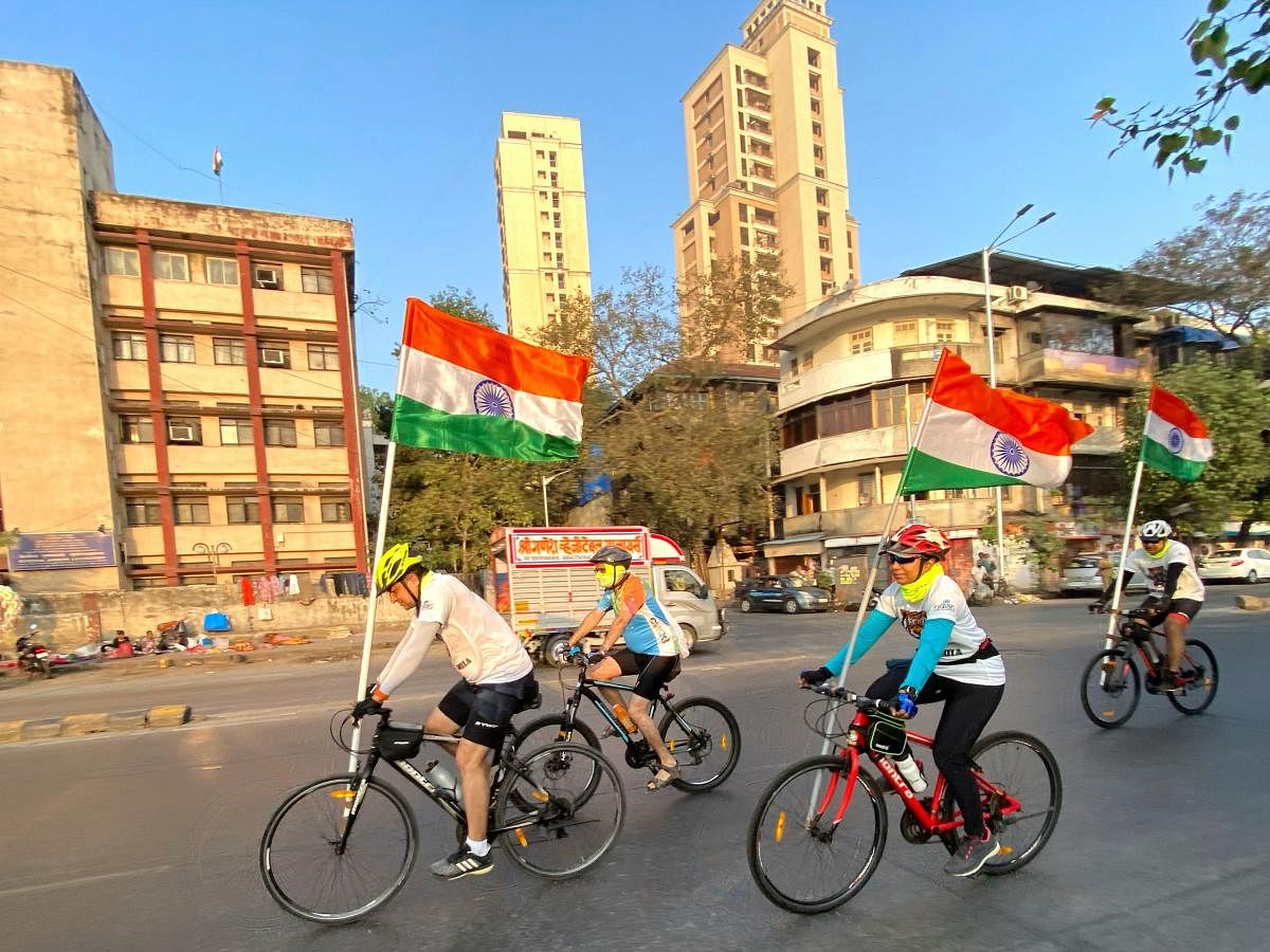 People cycle on a road with national flags during Republic Day celebrations in Mumbai on January 26, 2021. Credit: AFP Photo