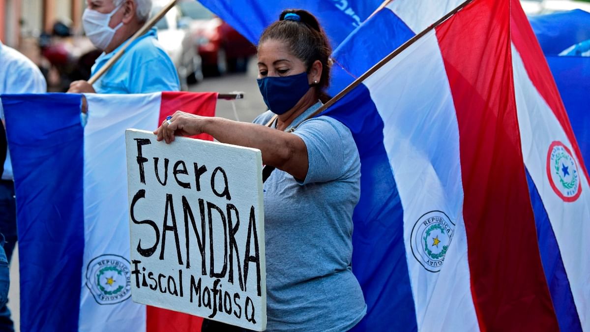 A woman holds a sign reading “Sandra out, racketeer General Attorney” during a protest demanding the resignation or impeachment of General Attorney Sandra Quinonez for alleged corruption in Asuncion. Credit: AFP Photo