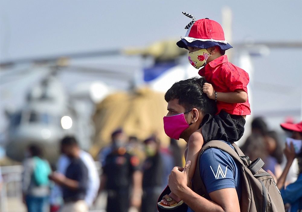 A man carries a child to view various aircrafts on static display during rehearsals for the Aero India 2021, at the Yelahanka air base in Bengaluru. Credit: PTI Photo