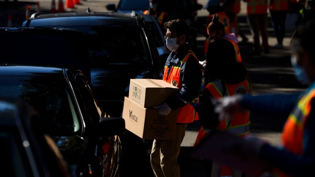 Workers load boxes of groceries into vehicles at a mobile food distribution from the Los Angeles Regional Food Bank at the Hollywood Bowl during the Covid-19 pandemic in Los Angeles, California. Credit: AFP Photo.