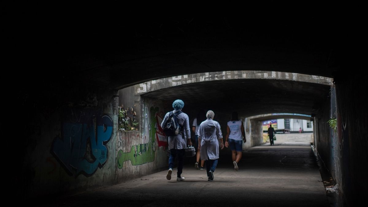 Health professionals are seen walking towards the house of a patient to inoculate him with Sinovac Biotech's CoronaVac vaccine against Covid-19, as part of a program attending elderly unable to get to one of the vaccination centers in Rio de Janeiro, Brazil. Credit: AFP Photo.
