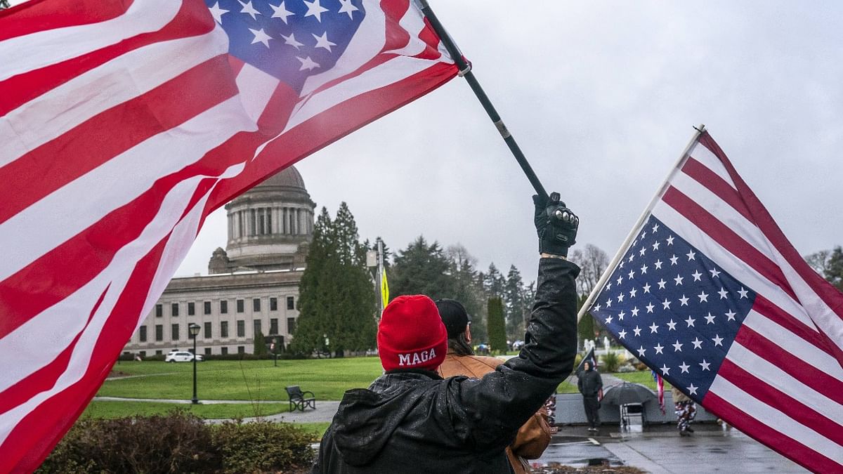 A self-identified member of the Patriot movement flies an upside down American Flag in Olympia, Washington. Right-wing protesters have been mostly quiet in the West following the inauguration of President Joe Biden. Credit: AFP Photo