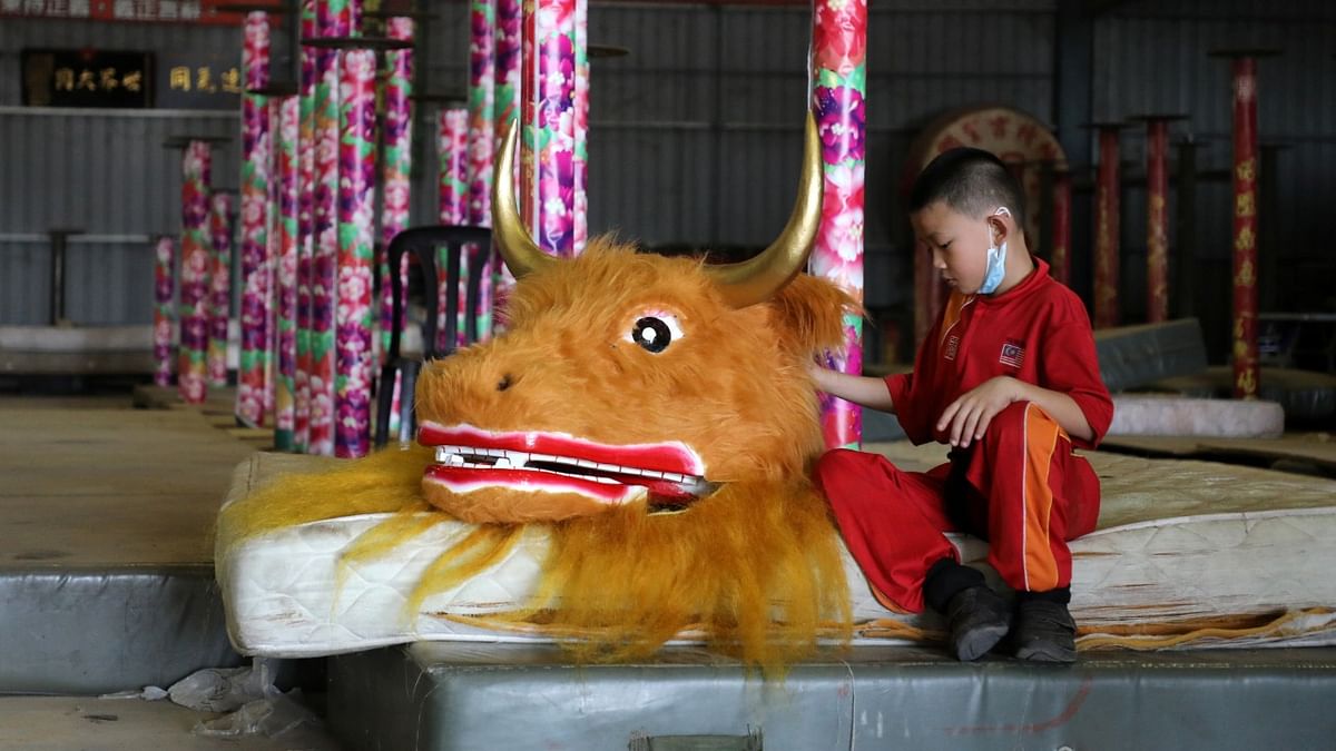A member of the Kun Seng Keng Lion and Dragon Dance Association, touches an ox mask designed for Lunar New Year at a training centre, in Muar, Malaysia. Credit: Reuters Photo.