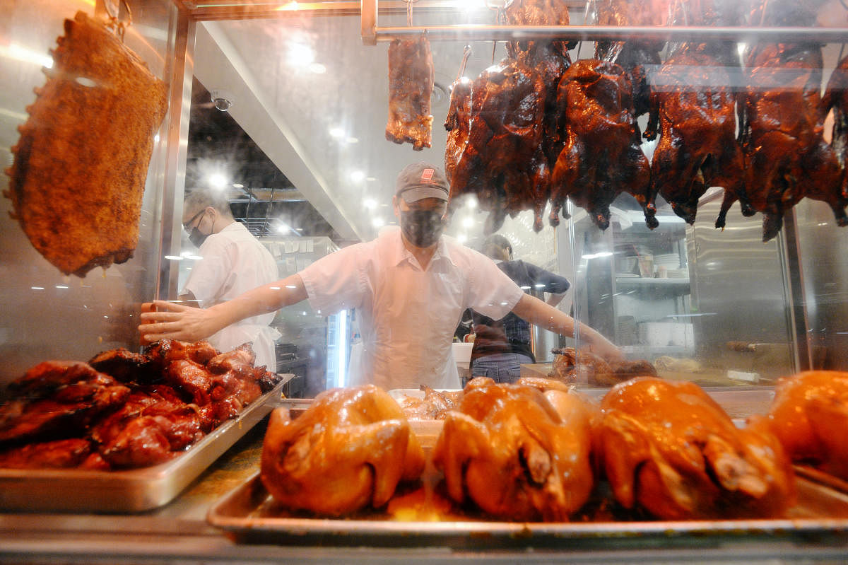 An employee reaches for roasted meat in the display window at HK BBQ Master on No. 3 Road, a Hong Kong style barbecue that is a crowd favourite among Hong Kongers in Richmond, British Columbia, Canada. Credit: Reuters photo.