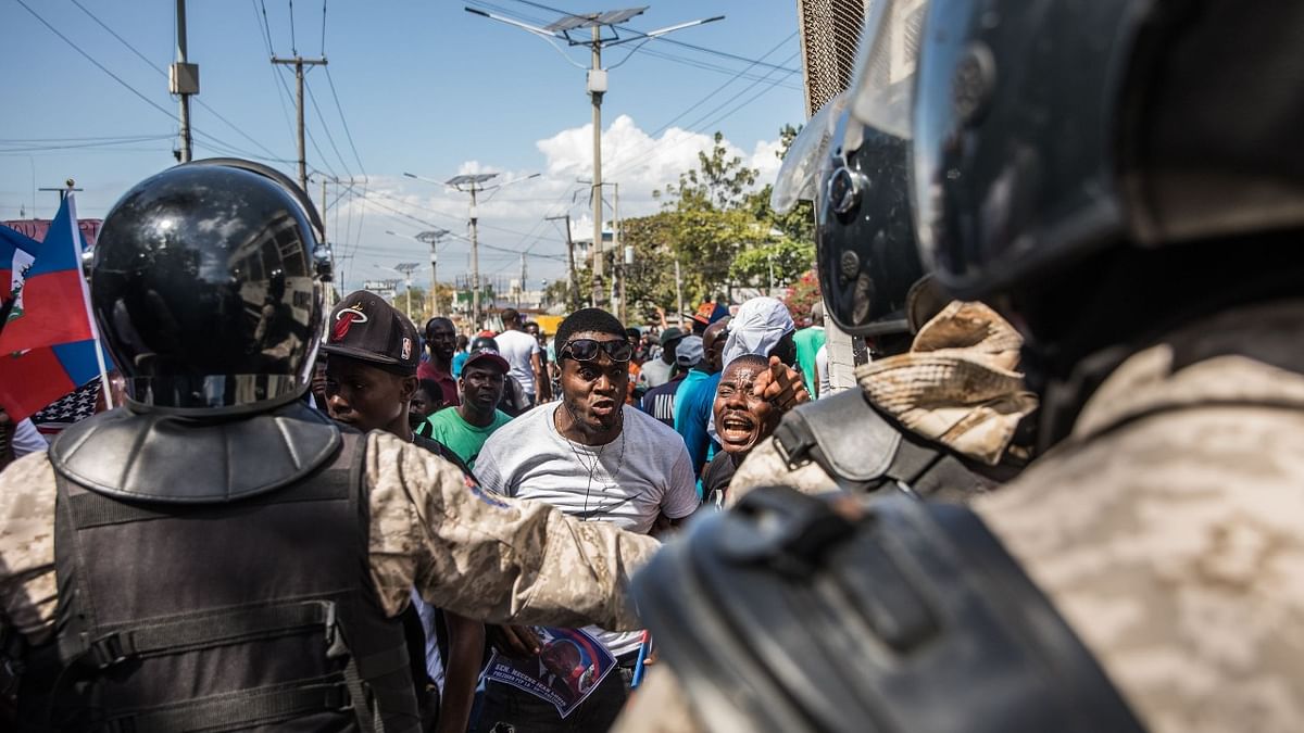 Demonstrators confront police officers as they march in Port-au-Prince on February 14, 2021, to protest against the government of President Jovenel Moise. Credit: AFP Photo.