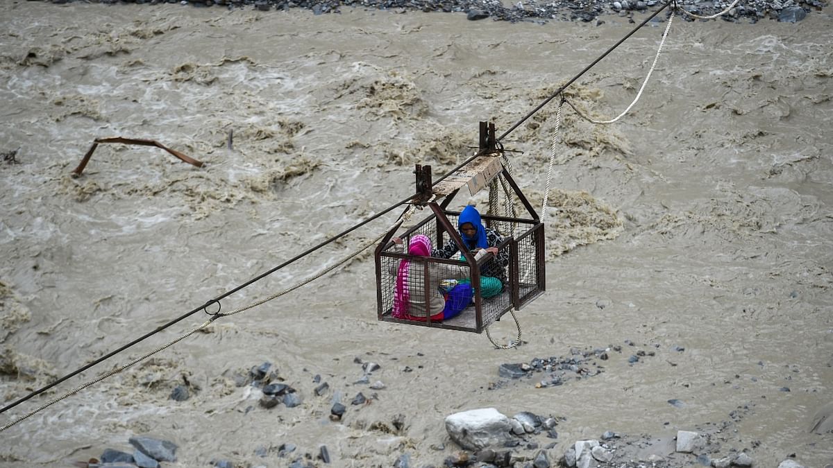 Villagers cross a river in an aerial cableway, a week after glacier burst on Feb. 7 in Joshimath triggered a flash flood, in Chamoli district of Uttarakhand. Credit: PTI Photo.