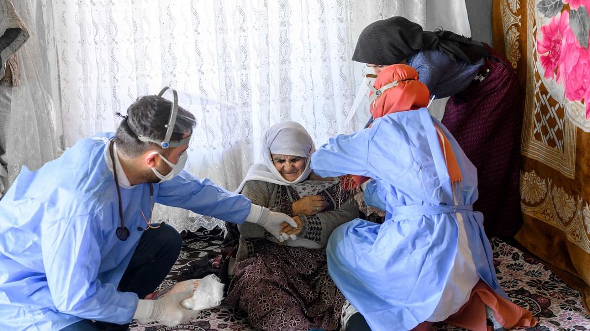Berfo Arsakay (C), 101 years old, receives a vaccine from nurse Yildiz Ayten (R) from the Bahcesaray public hospital vaccination team, at the village of Guneyyamac in eastern Turkey, as part of an expedition to vaccinate residents of 65 years old or above with Sinovac's CoronaVac Covid-19 vaccine. AFP Photo