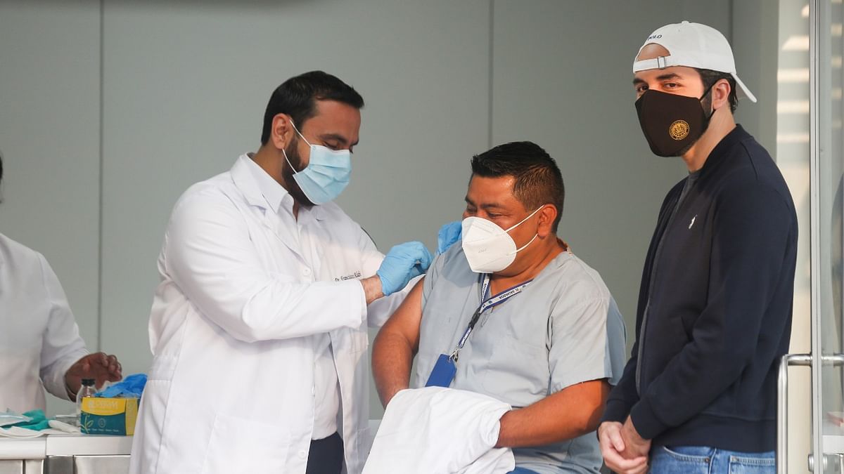 El Salvador's Minister of Health Francisco Alabi administers a dose of the AstraZeneca Covid-19 vaccine to a health worker, as El Salvador's President Nayib Bukele looks on, at a public health center in San Salvador, El Salvador. Credit: Reuters Photo