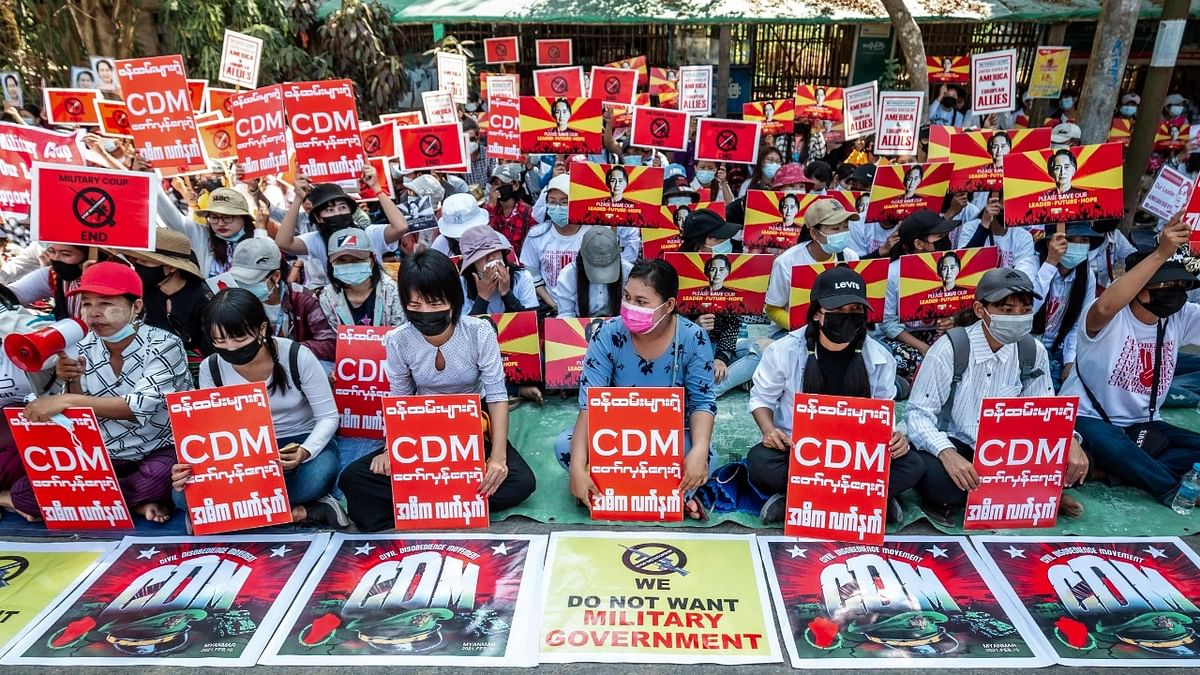Protesters display signs during in a demonstration against the military coup in front of the government administration office in Twante township, Yangon region Credit: AFP Photo
