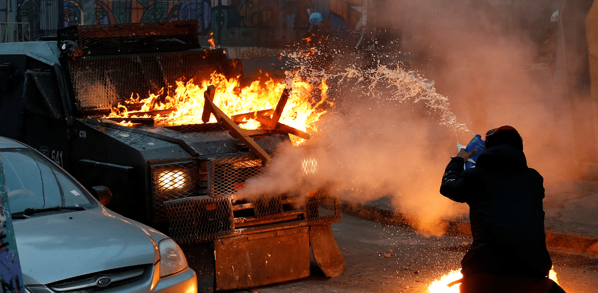 A demonstrator throws fuel at a police vehicle during a protest against Chile's government in Valparaiso, Chile. Credit: Reuters Photo